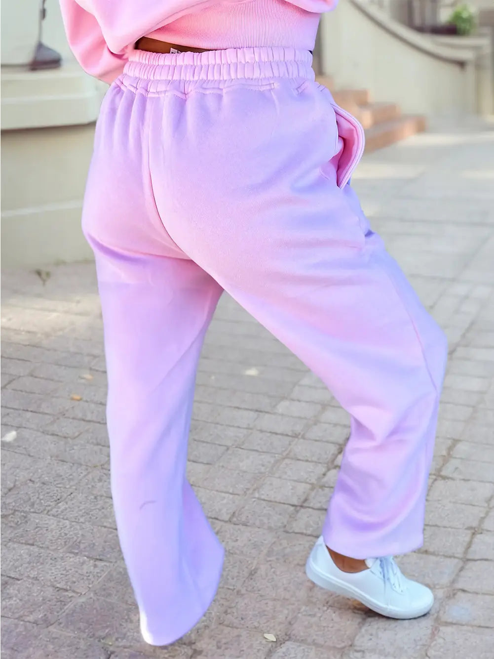 Person wearing pastel pink and purple pants on a stone pavement.