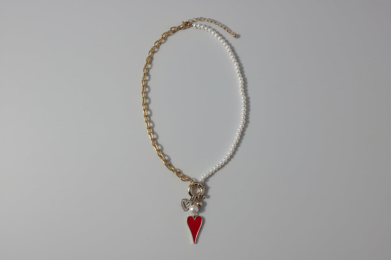 Necklace with a red heart charm on a snowy background
